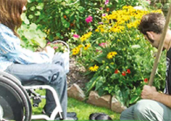 Ambulante-Dienste-eV-Muenster Ein Mann im Rollstuhl und eine Frau in einem Garten.